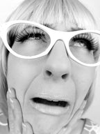 Black and white close-up of a person wearing large white sunglasses.