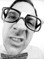 Black and white photo of a person wearing large glasses and a patterned bowtie.