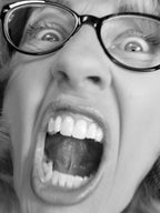 Close-up of a person wearing glasses with an open mouth expression.